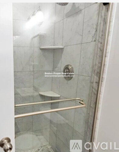A shower area with a glass door and a metal rail.