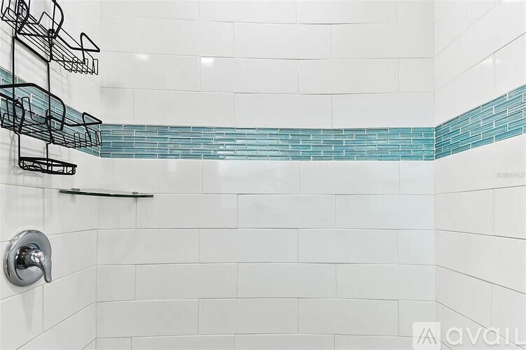 A shower with a blue tile strip and a silver faucet.