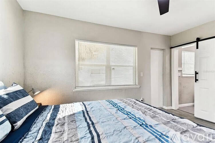 A bedroom with a bed and a window with blinds.