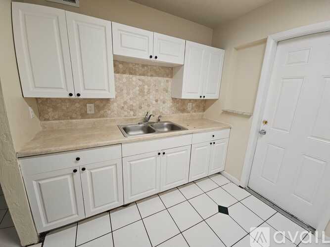 A kitchen with white cabinets and a tiled floor.