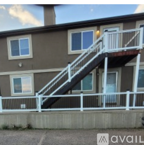 A brown building with a white railing and a staircase leading to the second floor.