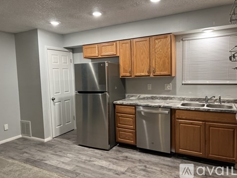 A kitchen with a refrigerator, sink, and cabinets.