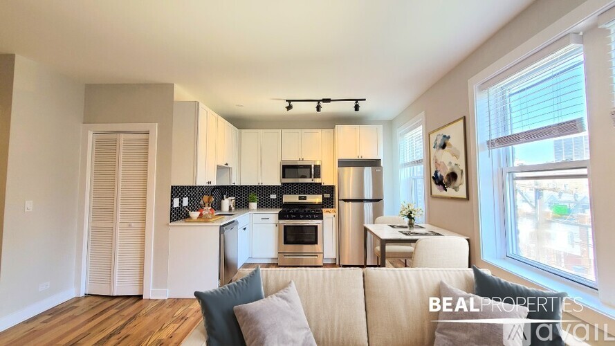 A modern kitchen with white cabinets and a wooden floor.