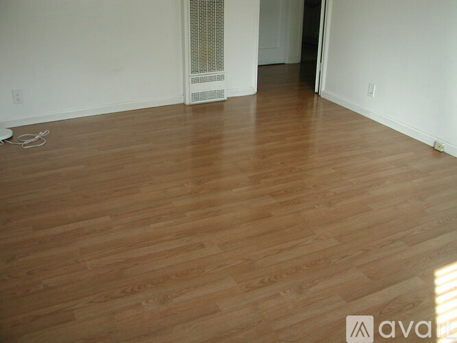 A room with wooden flooring and white walls.