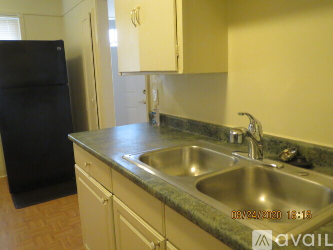 A kitchen with a black refrigerator and a stainless steel sink.