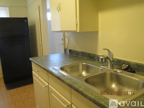A kitchen with a black refrigerator and a stainless steel sink.