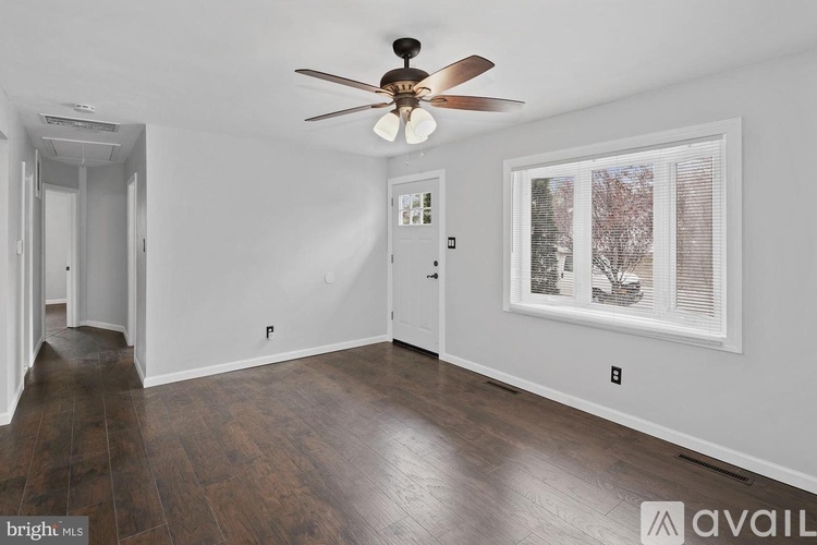 A room with a ceiling fan and a window with blinds.