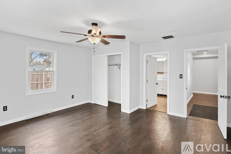 A spacious room with a ceiling fan and wooden flooring.