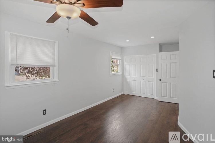 A room with a ceiling fan and wooden flooring.