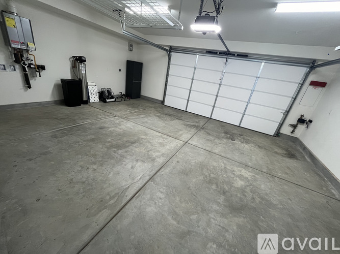 A spacious garage with a concrete floor and a white roller shutter door.
