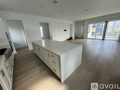 A spacious kitchen with white cabinets and wooden flooring.
