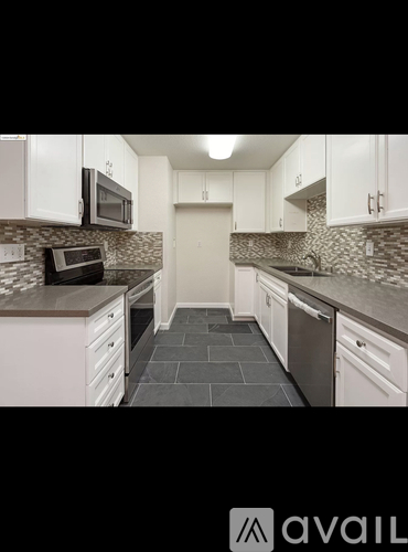 A kitchen with white cabinets and a black countertop.