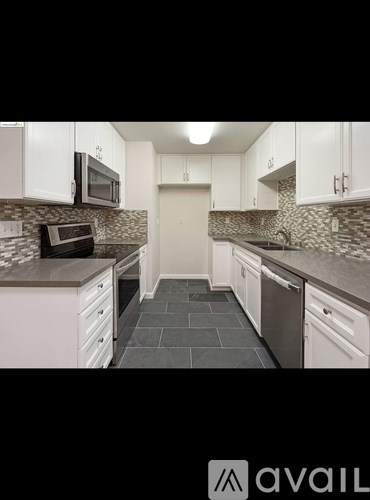 A kitchen with white cabinets and a black countertop.