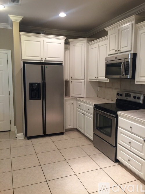 A kitchen with white cabinets and a stainless steel refrigerator.