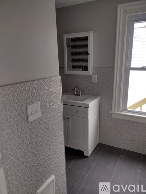 A bathroom with a white cabinet and a window.