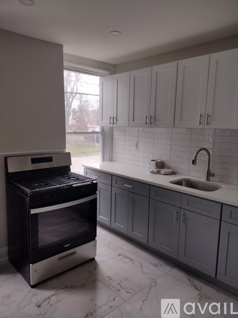 A kitchen with a black oven and grey cabinets.