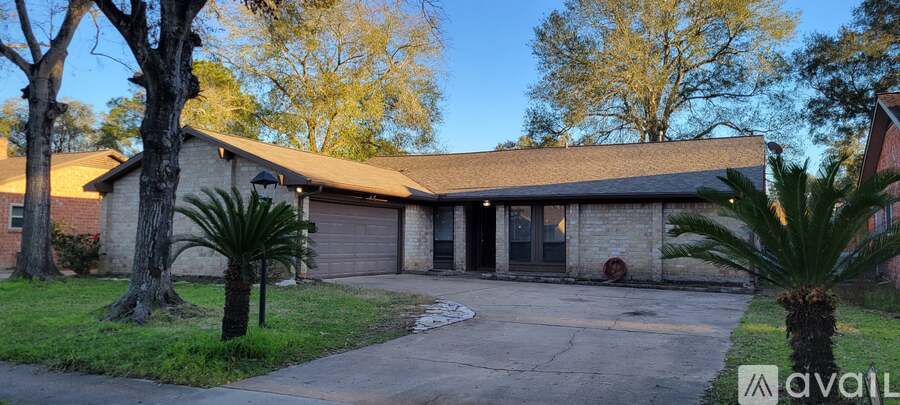 A house with a driveway and a palm tree in front.