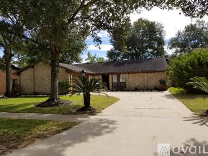 A house with a driveway and trees in front.