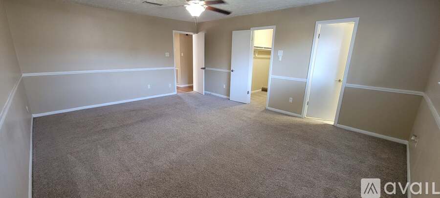 A spacious room with a carpeted floor and a ceiling fan.