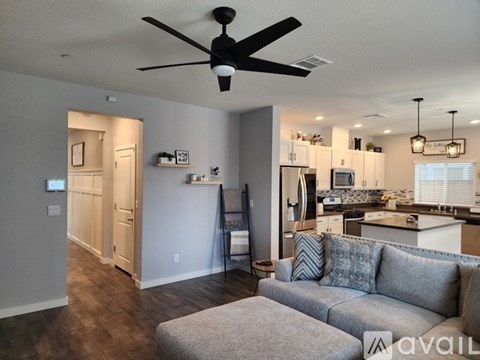 A living room with a grey couch and a ceiling fan.