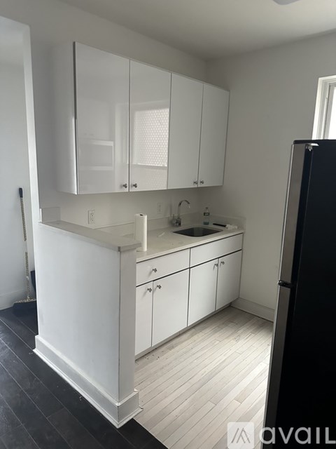 A kitchen with white cabinets and a black refrigerator.