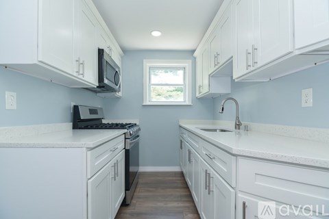 A kitchen with white cabinets and a window.