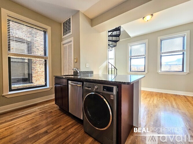 A washer and dryer are sitting on a counter in a room with wood floors.