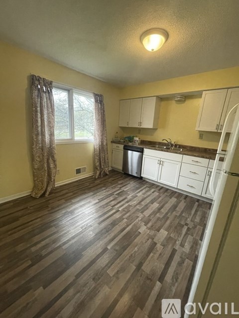 A kitchen with wooden floors and white cabinets.