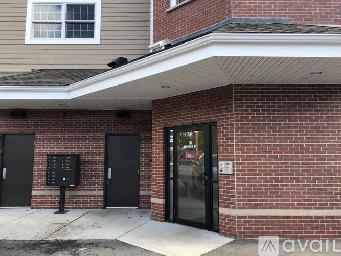 A brick building with a black door and a window above it.