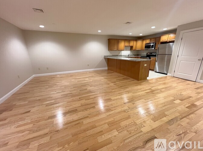 A kitchen with wooden flooring and a countertop with a refrigerator, microwave, and oven.