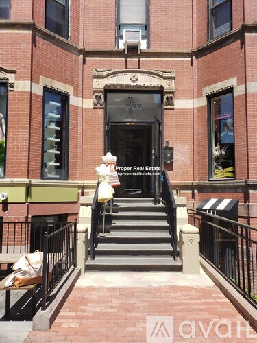 A brick building with a staircase leading to a door with a sign above it.