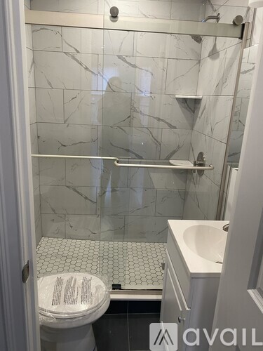 A white toilet with a marble patterned wall behind it.