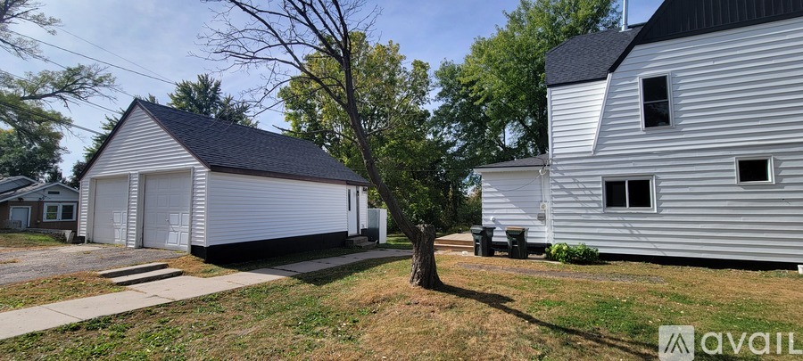 A white house with a black roof is situated in a grassy area.