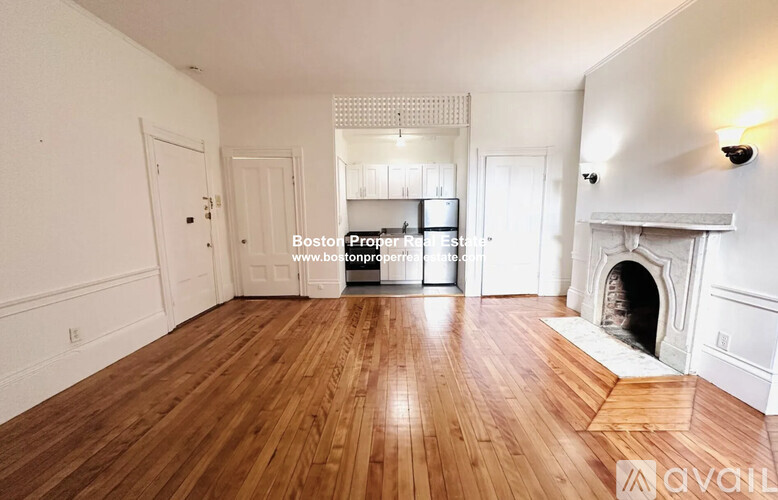 A spacious room with wooden floors and a fireplace.