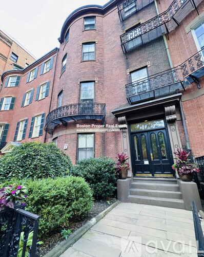 A red brick building with a black door and a balcony.
