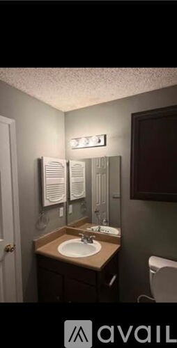 A bathroom with a sink, mirror, and towel rack.