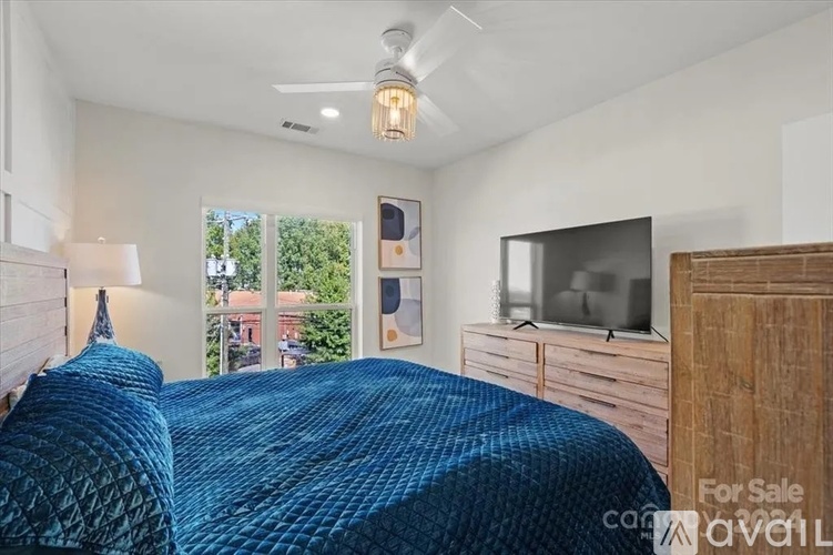A bedroom with a bed, a television, and a window with a view of a backyard.