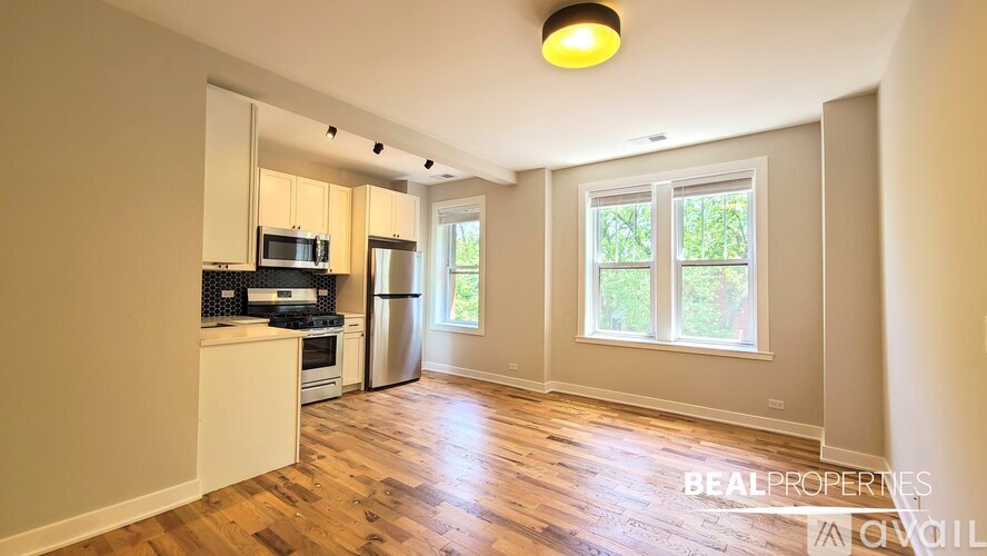A spacious kitchen with wooden floors and a large window.