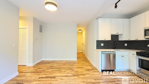 A kitchen with white cabinets and a wooden floor.