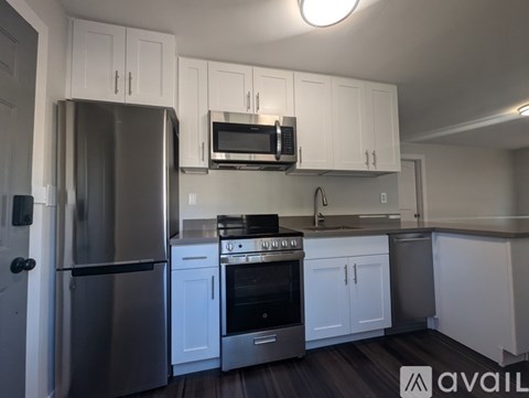 A kitchen with white cabinets and a stainless steel refrigerator.