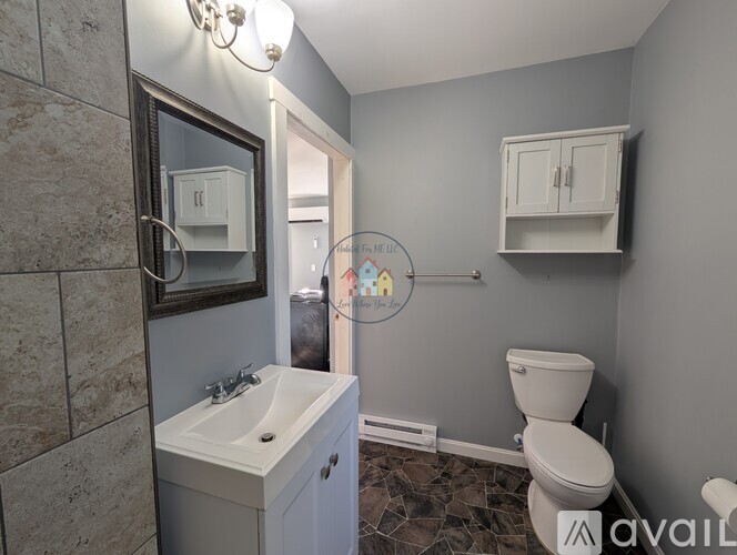 A bathroom with a toilet, sink, and mirror.