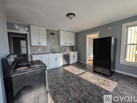 A kitchen with a black fridge and a black stove top oven.