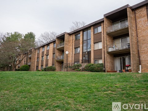 A brick apartment building with balconies and a green lawn in front.
