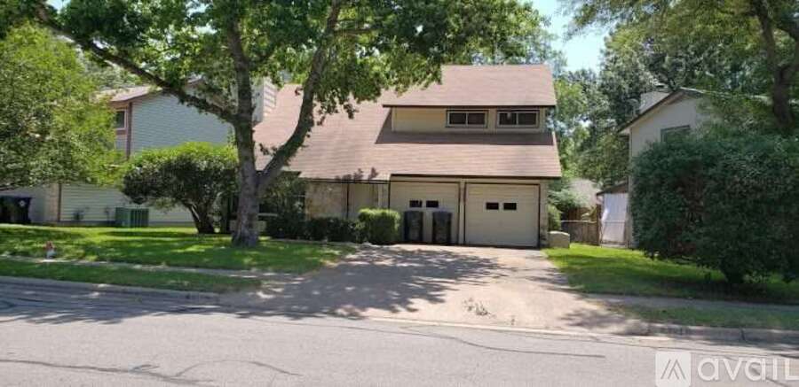 A house with a garage is surrounded by greenery.