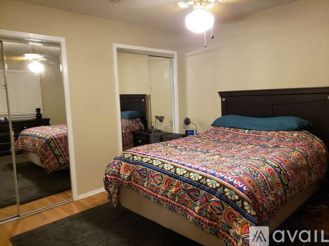 A bedroom with a bed covered in a colorful patterned bedspread.