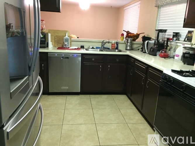 A kitchen with a refrigerator on the left and a dishwasher in the middle.