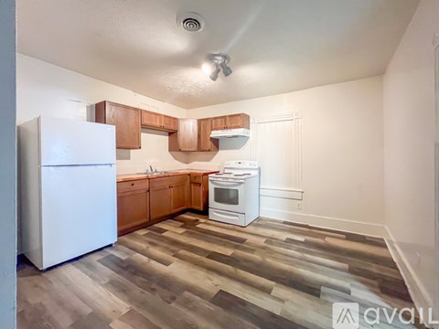 A kitchen with wooden floors and white appliances.