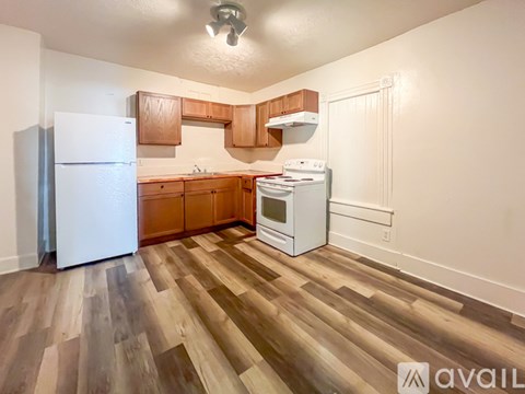 A kitchen with wooden floors and white appliances.
