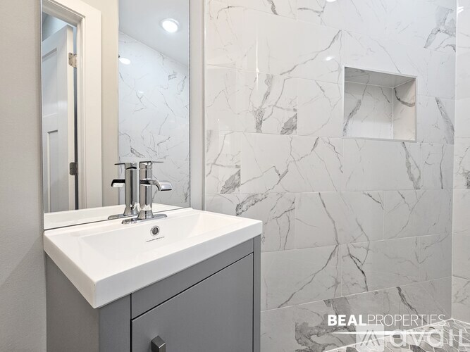 A bathroom with a marble wall and a white sink.