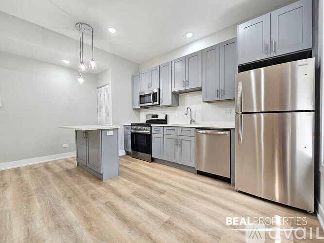 A modern kitchen with a stainless steel refrigerator and wooden flooring.